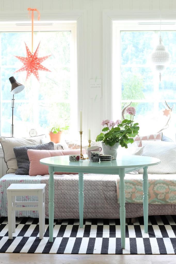 Bright dining corner with a mint table, white chairs and fresh flowers by the window