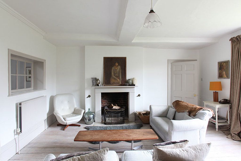 Calm white living room with a fireplace, soft armchairs and a wooden coffee table