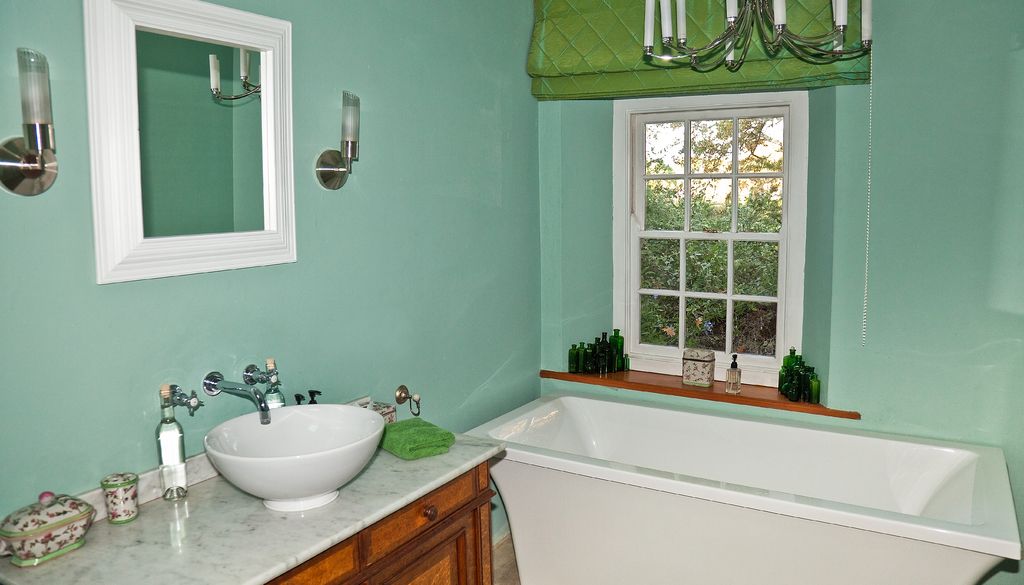 Fresh mint green bathroom with a bathtub, vessel sink and garden window