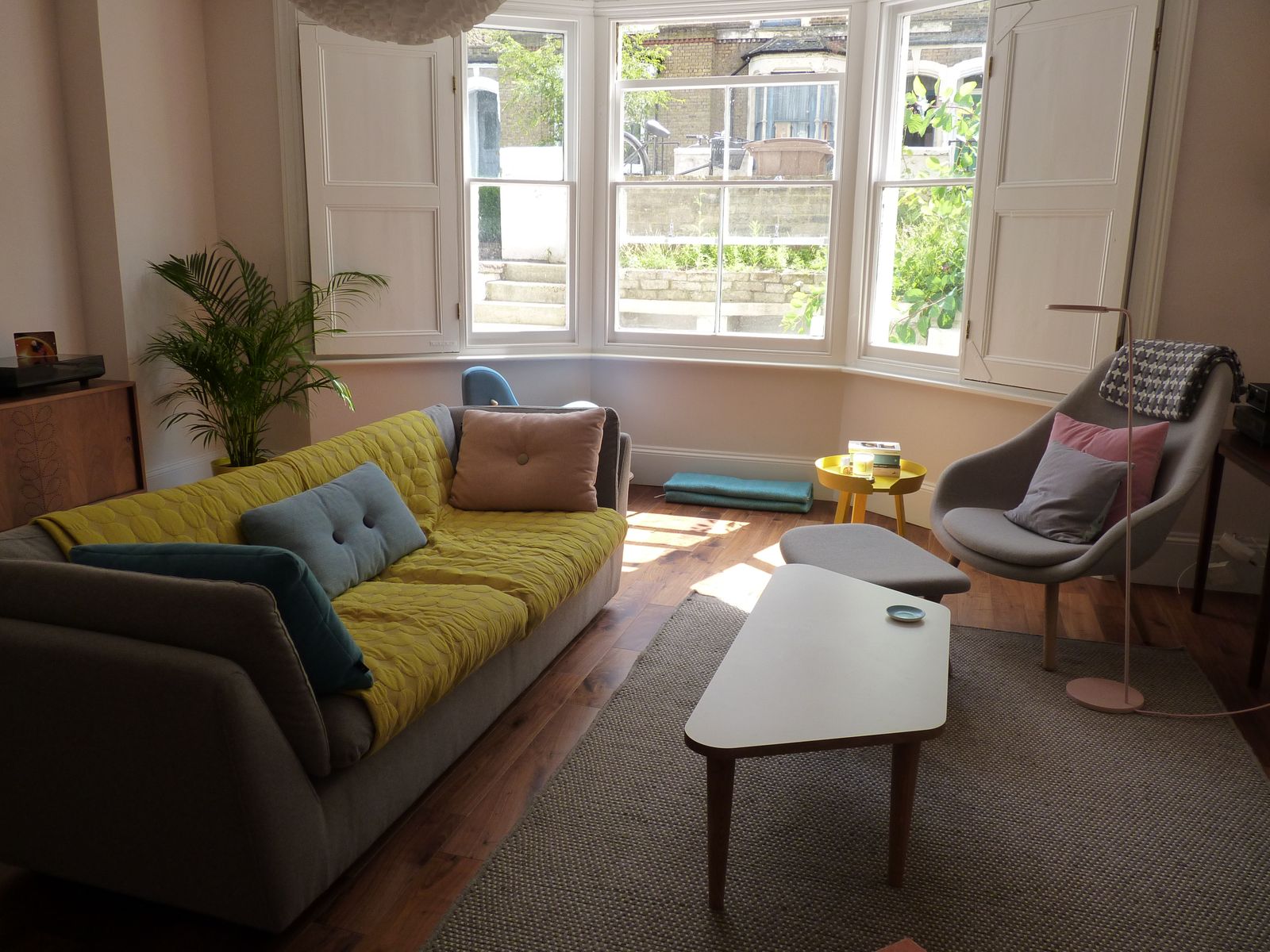 Bright, comfortable living room with a yellow sofa, soft cushions and a bay window