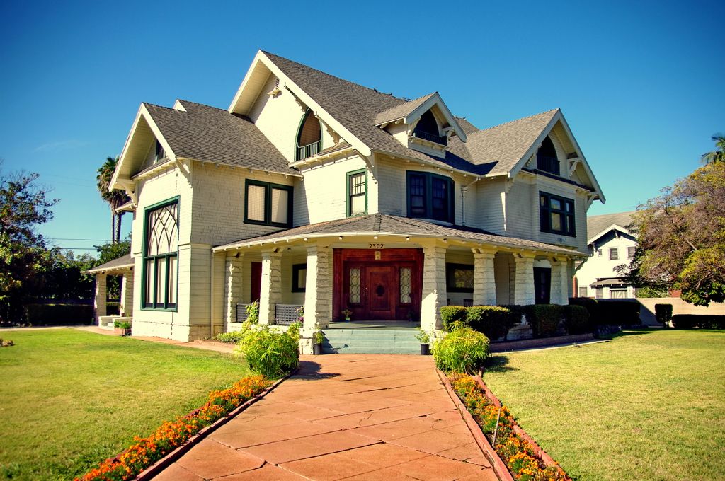 Large family home with a wide porch and a brick path through the lawn