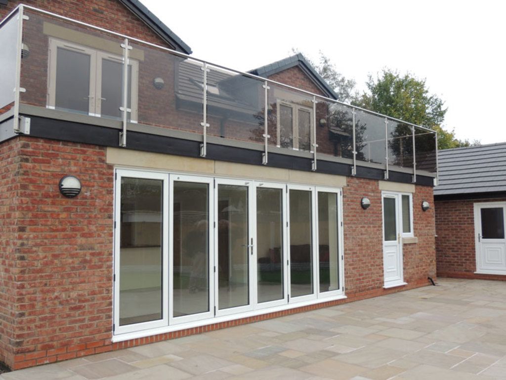 Brick home extension with wide folding glass doors opening onto a stone patio